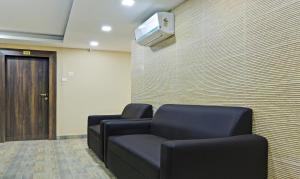 una sala d'attesa con due sedie e una tv a muro di Treebo Trend Raj Inn Lalpur a Rānchī