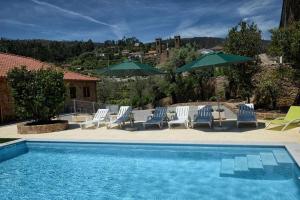 a swimming pool with lounge chairs and umbrellas at Casa do Tanque Camélias de Basto in Celorico de Basto