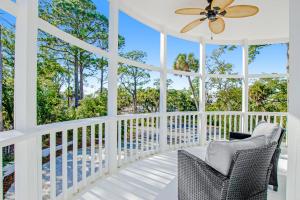 a white screened porch with a ceiling fan and chairs at Tybee White Mansion in Tybee Island