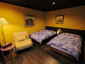 a bedroom with two beds and a chair and a lamp at Ryokan Tanoya in Kyoto