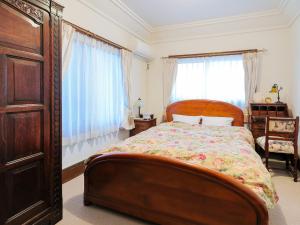 a bedroom with a bed and a dresser and windows at Ryokan Tanoya in Kyoto