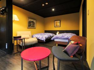 a room with two beds and a table and chairs at Ryokan Tanoya in Kyoto