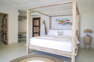 um quarto com uma cama de dossel em madeira com lençóis brancos em Theodor at Labuan Bajo em Labuan Bajo