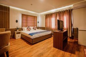 um quarto de hotel com uma cama e uma televisão em Stilly Inn em Patan