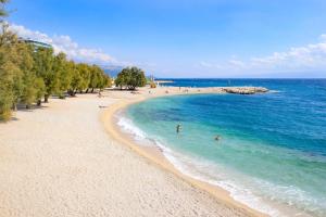 ein Strand mit Menschen, die im Wasser schwimmen in der Unterkunft Apartmant with Pool 8 in Kaštela