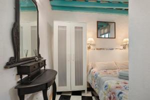- une chambre avec un lit et un miroir mural dans l'établissement Casa Lola, à Vejer de la Frontera