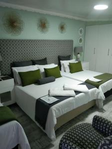 1 dormitorio con 2 camas grandes y almohadas verdes en Mitchell's Guesthouse, en Parow