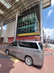 una minivan plateada estacionada frente a un hotel en Hotel Oasis, en Batang Kali