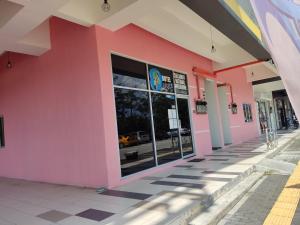 un bâtiment rose avec des fenêtres sur une rue dans l'établissement Hotel Oasis, à Batang Kali