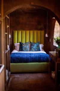 a bed with a yellow headboard in a room at Le Héritage in Klein-Drakenstein