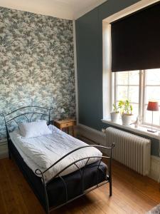 ein Schlafzimmer mit einem Bett und einer Wand mit Blumentapete in der Unterkunft Ting1903 Bed & Breakfast in Avesta