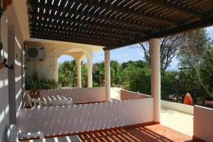 an outdoor patio with white chairs and a pergola at Oasi Di Casablanca in Lampedusa
