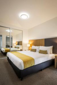 a large hotel room with two beds and a mirror at Quest King William South in Adelaide