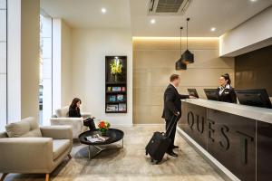 a man and a woman standing at a counter in a lobby at Quest King William South in Adelaide