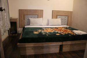 a bed with a green comforter with flowers on it at Baltit Heritage Inn in Hunza Valley