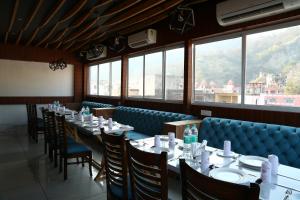 a dining room with tables and chairs and windows at Hotel Kush Ganga - 50 Meter from Har ki Pauri, Haridwar in Haridwār