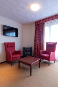 ein Wohnzimmer mit 2 roten Stühlen und einem Tisch in der Unterkunft Hotel Meyer in Bergen aan Zee