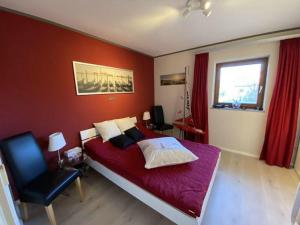 a bedroom with a large bed with a red wall at Ferienwohnung-Starkwind in Lemkenhafen auf Fehmarn