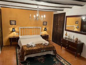 1 dormitorio con 1 cama, 2 mesas y lámpara de araña en CASA RURAL VICENTA 1750, en Albentosa