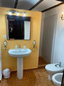 a bathroom with two sinks and a mirror and a toilet at CASA RURAL VICENTA 1750 in Albentosa