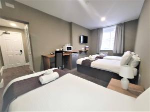 a hotel room with a bed, chair, desk and a television at New County Hotel by RoomsBooked in Gloucester