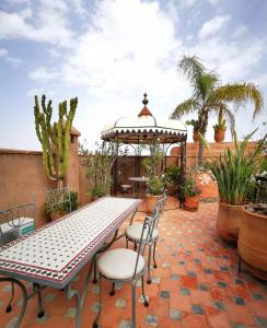 un patio con mesa, sillas y cenador en Riad Mehdia, en Marrakech