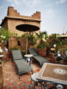 un patio con sillas, mesas y una sombrilla en Riad Mehdia, en Marrakech