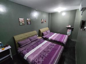 2 camas en una habitación con sábanas moradas en Hotel Oasis, en Batang Kali