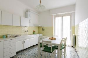 cocina con armarios blancos, mesa y sillas en JOIVY Family Flat Terrace & Parking near Beach en Sestri Levante