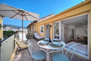 a patio with a table and chairs and an umbrella at IMMOGROOM - Splendid Terrace - Studio - Central in Cannes