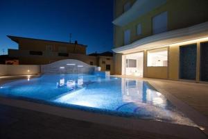 a large swimming pool with blue lighting in front of a building at Appartamento Vista Mare con Spiaggia e Piscina in Alba Adriatica