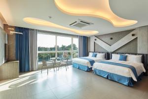 Cette chambre d'hôtel comprend deux lits, une table et des chaises. dans l'établissement Elren Hotel Jeju, à Seogwipo