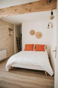 um quarto com uma cama branca e almofadas laranja em Maison de campagne avec salle de jeux 6 personnes em Cuq