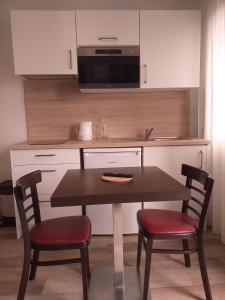 a kitchen with a table and chairs and a microwave at Brit Hotel Essentiel de Granville in Granville