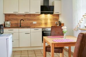 a kitchen with white cabinets and a wooden table at Ferienwohnung Patermann in Pommelsbrunn