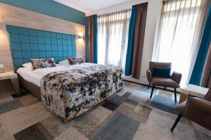 a bedroom with a bed and a chair and windows at Hotel Meyer in Bergen aan Zee