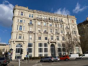 un grand bâtiment blanc avec des voitures garées devant lui dans l'établissement Balance Home, à Budapest