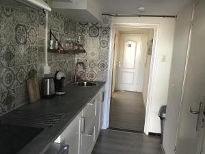 Una cocina con encimera y fregadero y un pasillo. en Life@Sea, en Zandvoort