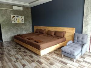 a bedroom with a large bed and a chair at JK Riverview Resort in Ban Song Phi Nong