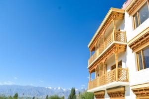 un edificio con balconi e montagne sullo sfondo di Hotel Deskitsal a Leh