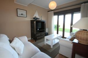 a living room with a white couch and a tv at El Balcón de Raquel in Comillas
