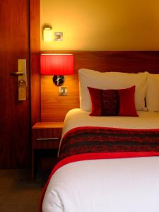 a bed in a hotel room with a red lamp at Orocco Pier in Queensferry