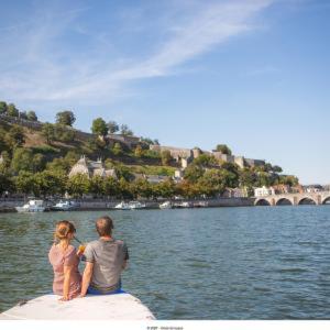 un hombre y una mujer sentados en un barco en el agua en la Rose sur Meuse, en Haybes