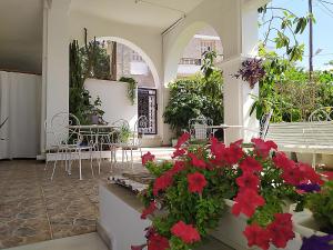 a patio with red flowers and tables and chairs at Pension Filitsa in Pylos