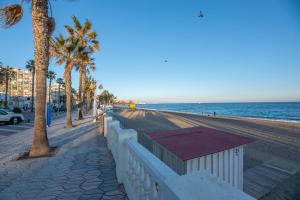 a beach with a fence and palm trees and the ocean at MODERN APARTMENT NEXT TO THE BEACH, Pets friendly in Benalmádena