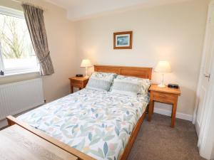 a bedroom with a bed and two night stands with lamps at Tilly Mint Cottage in Penrith +21 photos