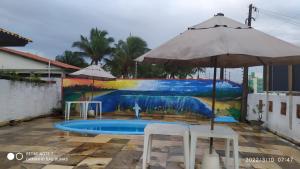 a pool with two chairs and an umbrella at Pousada Caminho das Dunas in Cumbuco