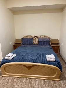 a bedroom with a large bed with blue sheets and blue pillows at Hotel Hovit in Bagratashen