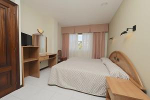 a bedroom with a bed and a desk and a television at Hotel Paraíso Del Marisco in O Grove
