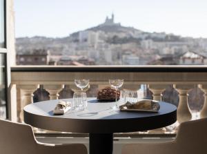 - une table avec des verres à vin et un gâteau sur le balcon dans l'établissement InterContinental Marseille - Hotel Dieu, an IHG Hotel, à Marseille